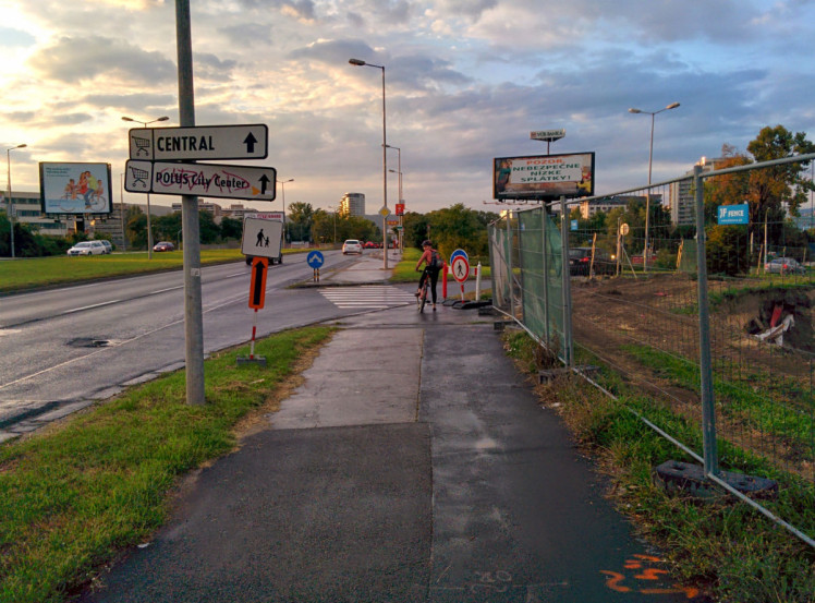 Cyklistka čakajúca na možnosť spustiť sa dole na Ružinovskú po ceste